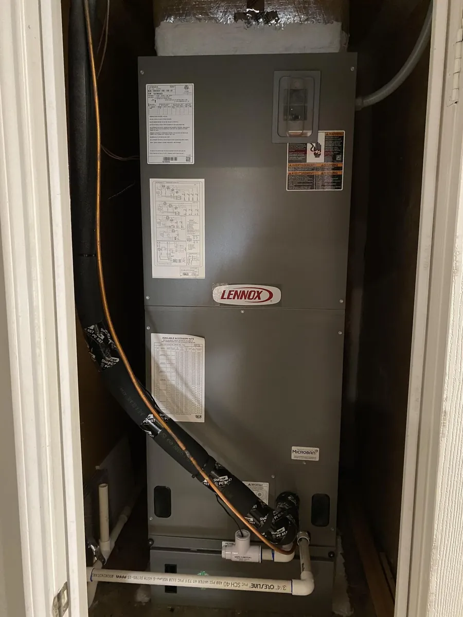 A Lennox air handler installed in a hall closet with insulated refrigerant lines and a PVC condensate drain with a safety switch